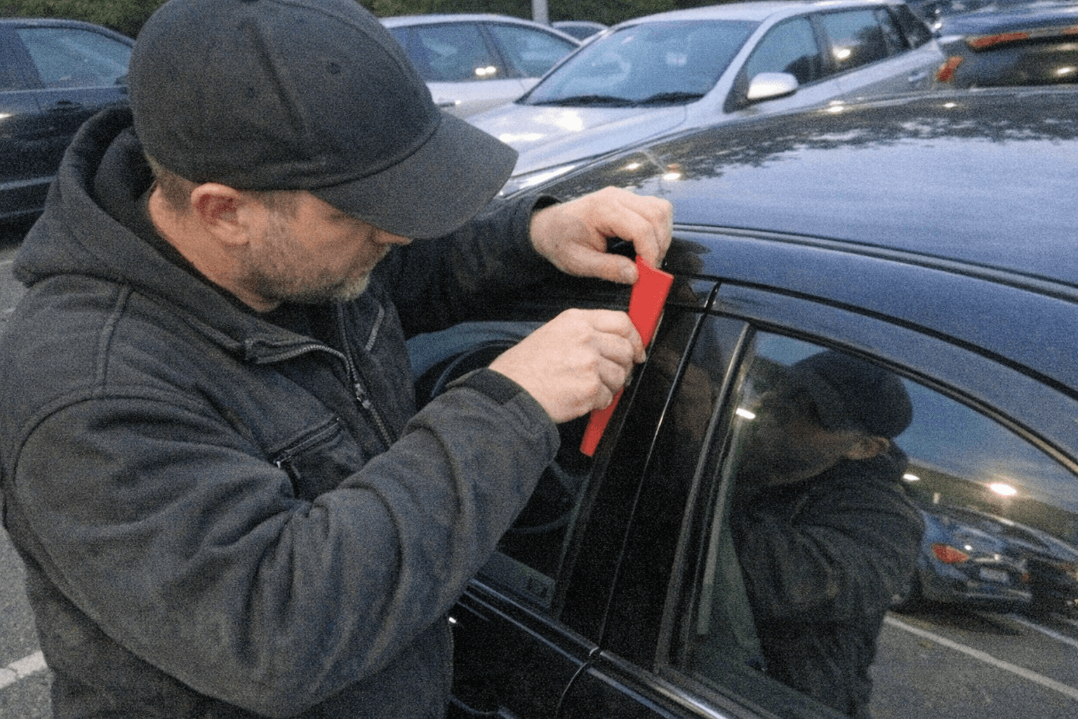 Spezialist öffnet schonend ein verriegeltes Fahrzeug auf dem Parkplatz